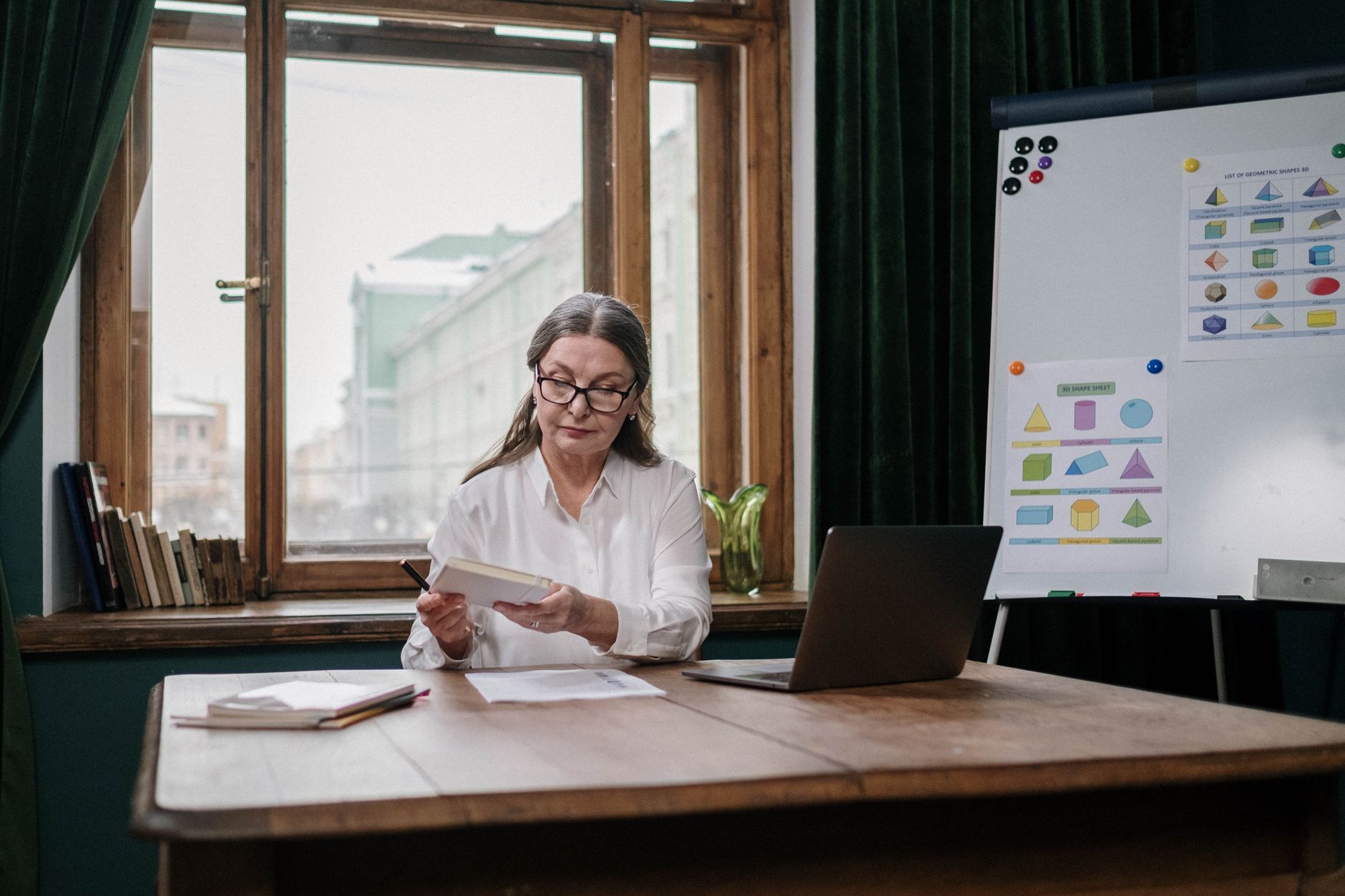 A school leader reviewing student paperwork by a classroom window